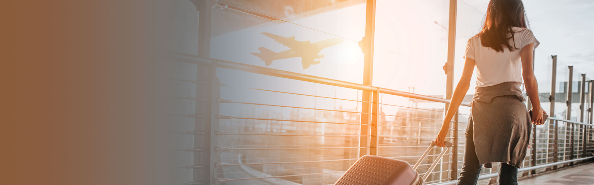 Travel nurse walking through the airport rolling her bag behind her as she looks out of window.