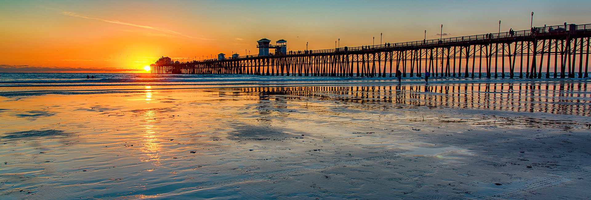 Scenic view of the sun setting on the ocean and sand from the shore.